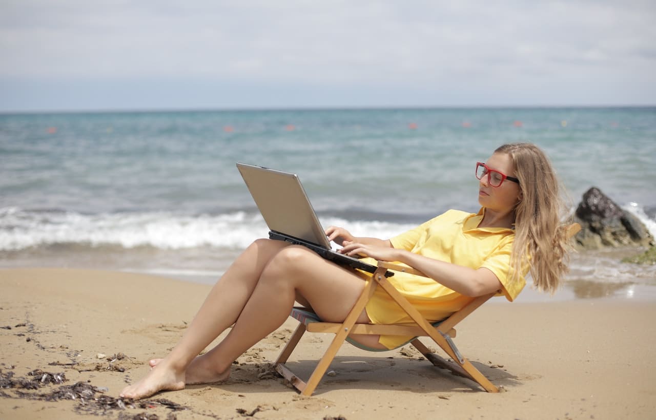 A Girl is Blogging at a Sea Beach with Her Laptop