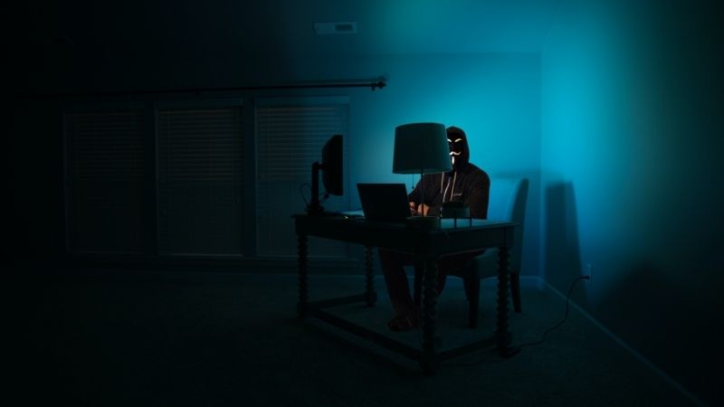 a man at a computer disguised as an anonymous